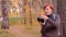 Portrait woman photographer using photo camera and doing shot in autumn forest