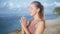 Portrait of woman practices yoga, concentrates on breathing at beach, slow motion
