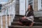 Portrait of a woman in profile sitting on the steps of a retro porch