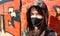 Portrait of a woman in a protective black mask outdoors near an old broken wall. Coronavirus and air pollution concept. A girl