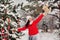 Portrait of a woman in a red jacket and a white hat in a cold winter forest and a toy in her hands. A girl in a snowy