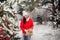 Portrait of a woman in a red jacket and a white hat in a cold winter forest and a toy in her hands. A girl in a snowy