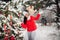 Portrait of a woman in a red jacket and a white hat in a cold winter forest and a toy in her hands. A girl in a snowy