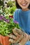 Portrait of woman showing potted flower in the garden