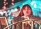 Portrait of woman sitting on bright Bokeh light on chair decoration in Outdoor Festive Market in Lush Lava color toned