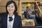 Portrait of woman smiling while female industrial worker driving forklift truck in background