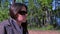 Portrait of woman in sunglasses sitting resting in forest on riverbank.