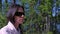 Portrait of woman in sunglasses sitting resting in forest on riverbank.