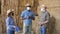 Portrait of woman and two men on straw stack, multiracial group of farmers in face masks for disease protection resting