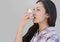 Portrait of woman using asthma inhaler with grey background