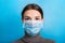 Portrait of a woman wearing medical mask with pandemic word at blue background. and healthcare concept