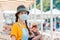 Portrait of a woman wearing a medical mask and straw hat. In the background there are sun beds and beach umbrellas. Concept of