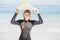 Portrait of woman in wetsuit carrying surfboard over head