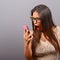 Portrait of a woman yelling at cellphone against gray background