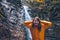 portrait of woman in yellow raincoat in front of autumn waterfall