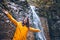 portrait of woman in yellow raincoat in front of autumn waterfall