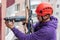 Portrait of a worker hanging on ropes and drilling a wall with a drill. High-altitude works concept.