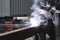 Portrait of worker in protective mask welds metal.