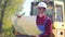 Portrait of a worker in a uniform and a white helmet on the background of special road equipment