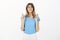 Portrait of worried intense attractive woman in blue t-shirt, raising crossed fingers and biting lip, frowning, feeling