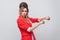 Portrait of worry beautiful business lady with hairstyle and makeup in red fancy blazer, standing and touching her hand to show