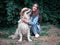 Portrait of yound happy woman playing with golden retriever labrador dog and straw hat