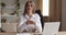 Portrait of young active smiling business woman sitting in office at table in successful company, talking to camera