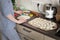 Portrait young adult brunette caucasian woman making dough with roller pin for sweet tasty homemade cookies at home