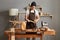 Portrait of young adult Caucasian craftsman using measuring tape to make marks on piece of wood placed, making wooden furniture in