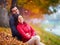 Portrait of young adult couple hugging among colorful fallen leaves in autumn park