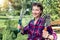 Portrait of young adult happy beautiful caucasian brunette woman grower worker holding shears and showel spade with green formal