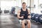 Portrait of young adult muscular built handsome athlete working out in a gym, sitting on a weightlifting machine and holding two