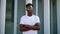 Portrait of young african american serious confident guy looking at camera with crossed arms standing outside. Handsome