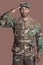 Portrait of a young African American US Marine Corps soldier saluting over brown background