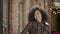 Portrait of young African American woman waving hand, showing gesture come here. Brunette in brown leather jacket posing