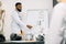 Portrait of young African male doctor or biochemist showing on board some biochemical formulas for his colleagues in