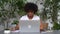 Portrait of young African woman college student thinking, typing on laptop, writing text notes in workbook, reading