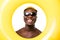 Portrait of young afro american man un sunglasses in summer clothes with yellow inflatable ring isolated on white background