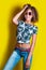 Portrait of a young afro american woman in sunglasses. Yellow background. Lifestyle.