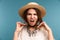 Portrait of a young angry girl in summer hat isolated over blue background,