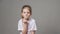 Portrait of young angry girl threatens with a shaking fist isolated on grey background. Concept of emotions.