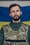 Portrait of young angry man in body armor with ukrainian flag on his face