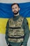Portrait of young angry man in body armor with ukrainian flag on his face