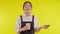 Portrait of young asian barista woman wearing apron smell coffee cup on yellow background.