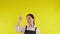 Portrait of young asian barista woman wearing apron standing and presenting on yellow background.