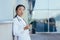 Portrait young Asian doctor woman or paramedic stands exhausted on a break near the wall of a hospital clinic with a using mobile