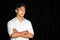 Portrait of a young asian handsome boy wearing white shirt crossing hands on the black background. Sadness expression feeling