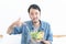 Portrait of young Asian man does not want to eat and has no appetite not eat salad. Adult man do not like to eat vegetables,