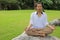 Portrait of young Asian man doing yoga meditation while sitting in lotus position on the rock in beautiful outdoor park.