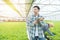 Portrait of young asian professional farmer man hand hold tablet with asian woman coworker working in greenhouse hydroponic